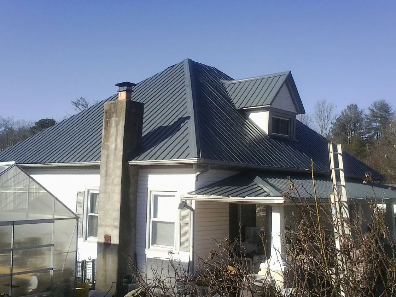 Dark blue standing seam metal roof on a white farmhouse with dormer — Slate & Tile Roof Repair by Roofing Brothers in Morgan