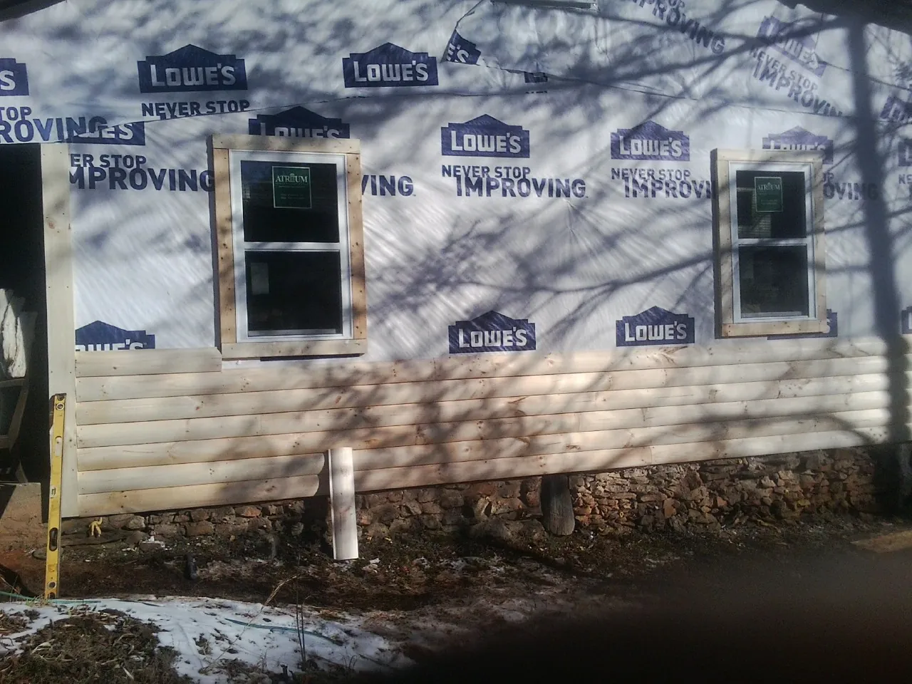 House wrap and new log siding going up on an exterior wall in Morgan