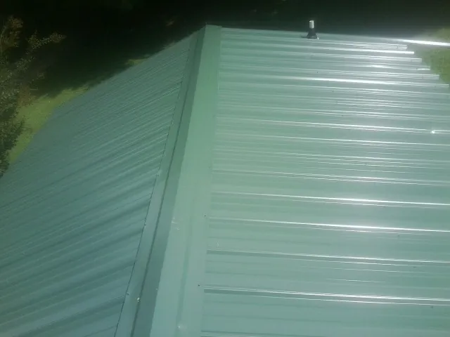 New green metal panels meeting at the ridge of a roof — Flat Roof Repair work by our crew in Morgan