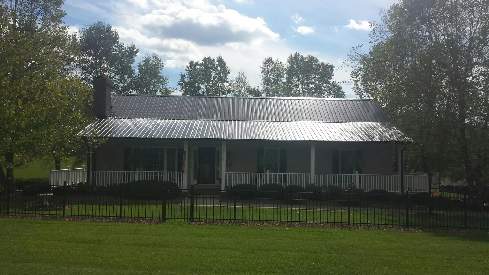Gray metal roof on a brick ranch with a full width front porch — Gutter Guard Installation work by our crew in Morgan