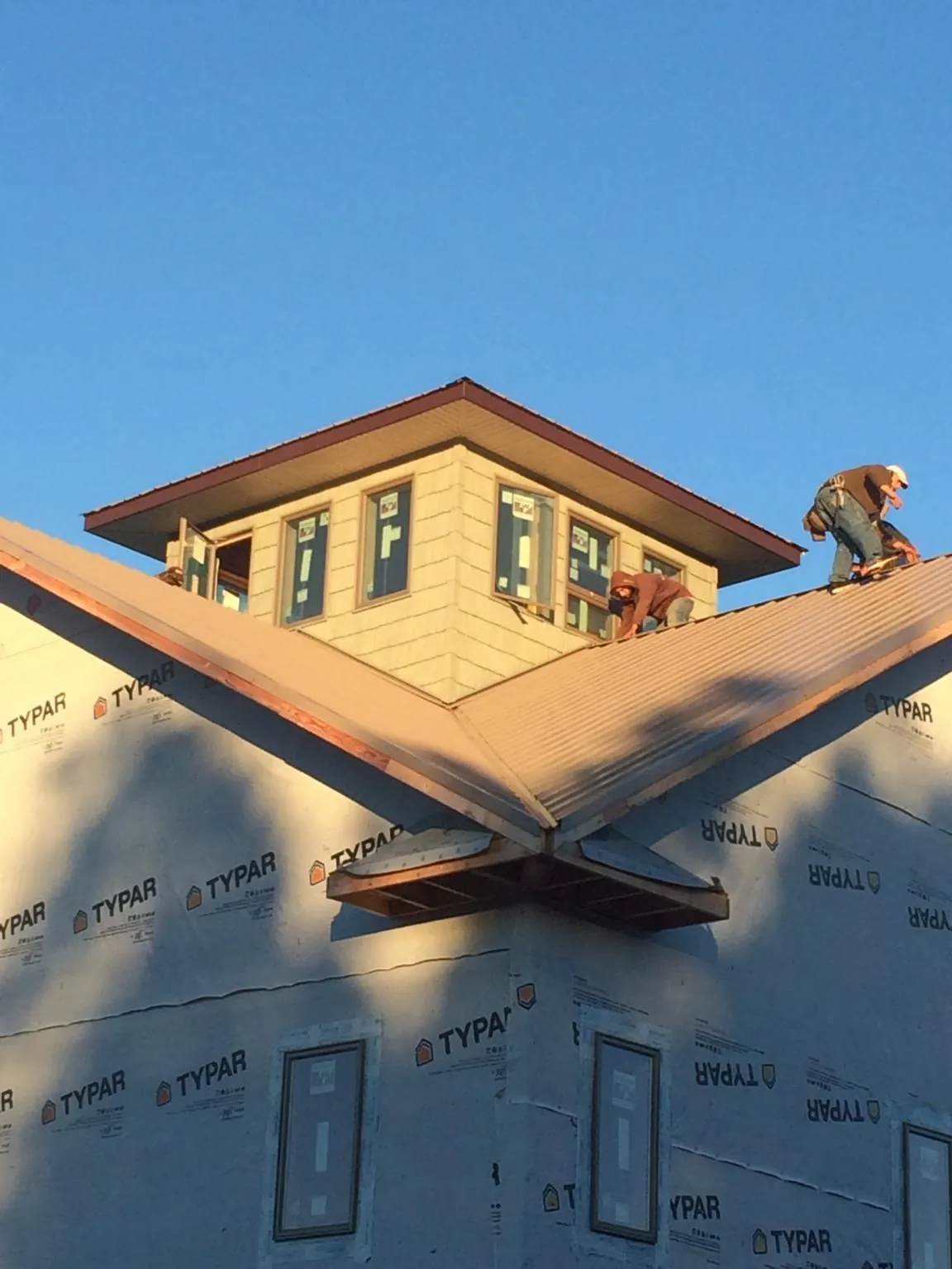 Roofers working around a rooftop cupola on a new metal roof at sunset — Roof Waterproofing in Morgan by Roofing Brothers